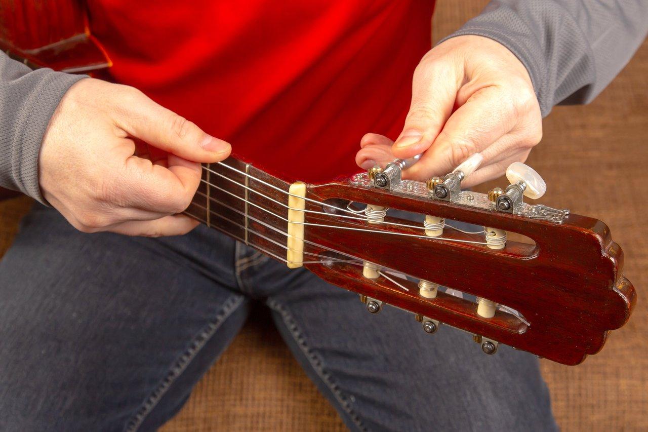 Atelier de luthier en pleine réparation d'une guitare électrique ancienne dans un guitar repair workshop.
