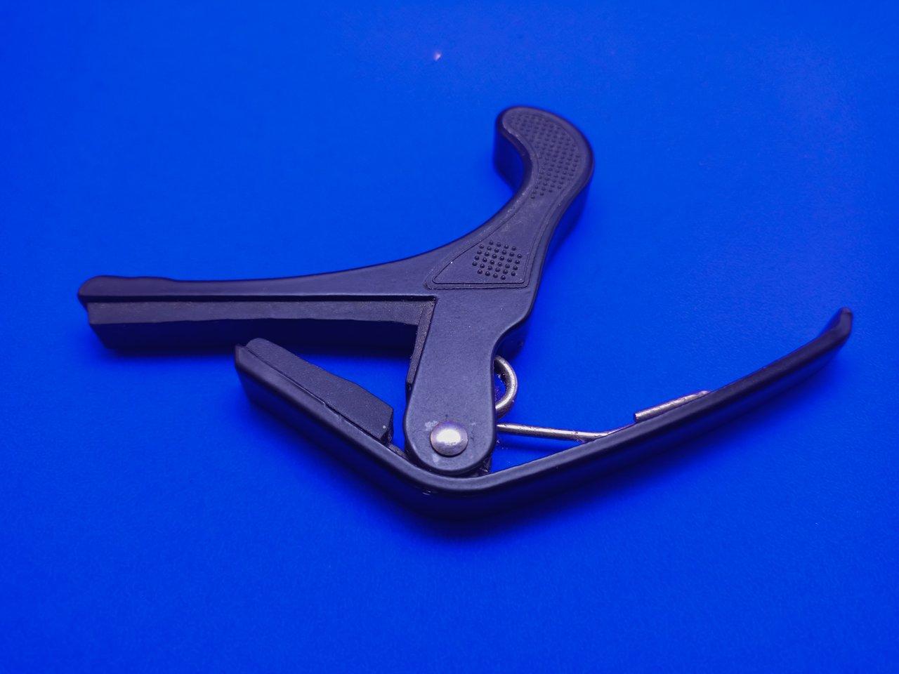 Capodastre guitare acoustique à ressort en gros plan, montrant la prise ergonomique et la fixation précise.