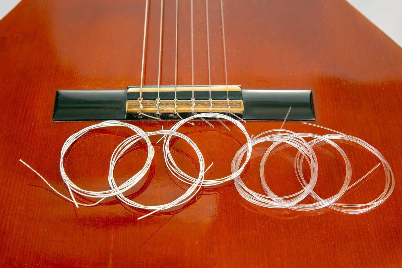 Cordes d'instruments écologiques en matériaux composites, prêtes à être installées sur une guitare acoustique rouge.