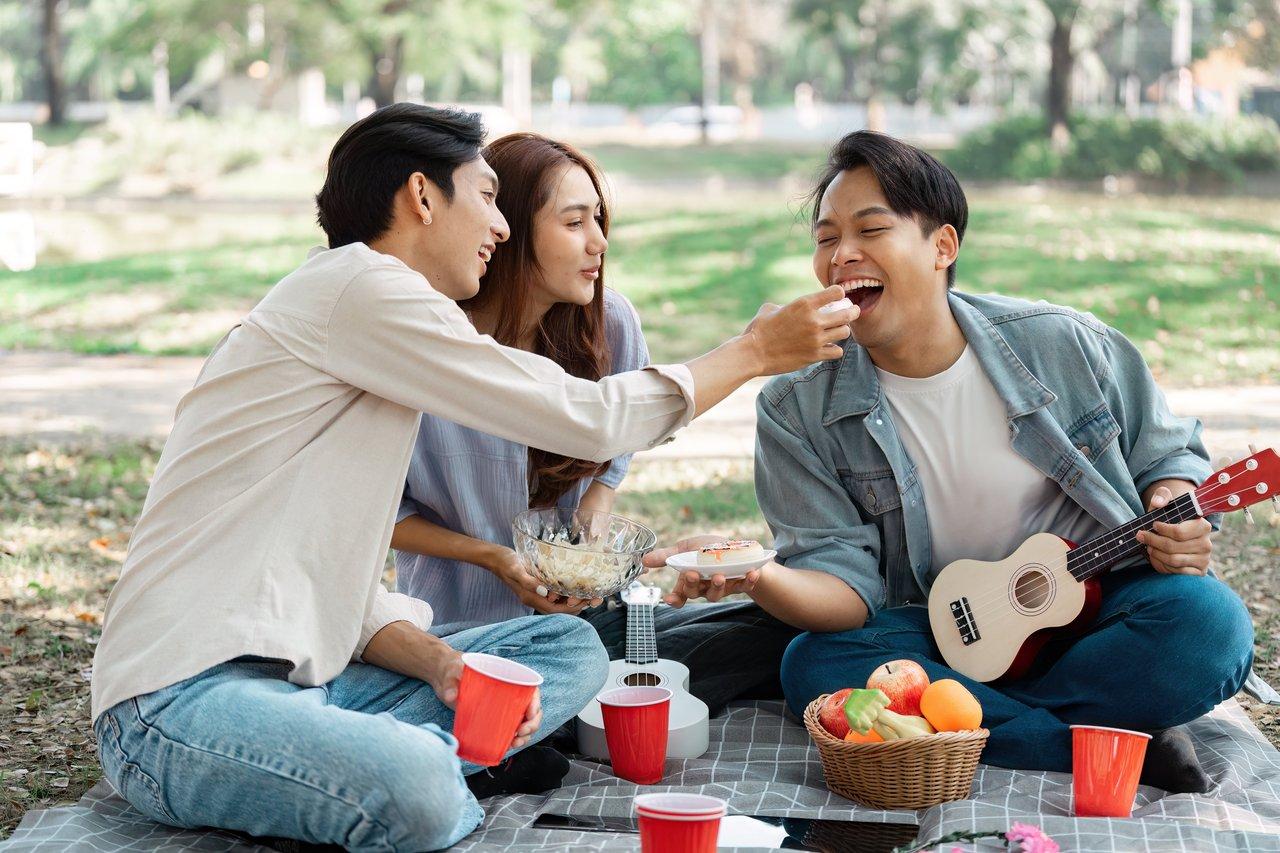 Ensemble d'amis profitant d’un pique-nique estival avec des enceintes Bluetooth portables pour festival.