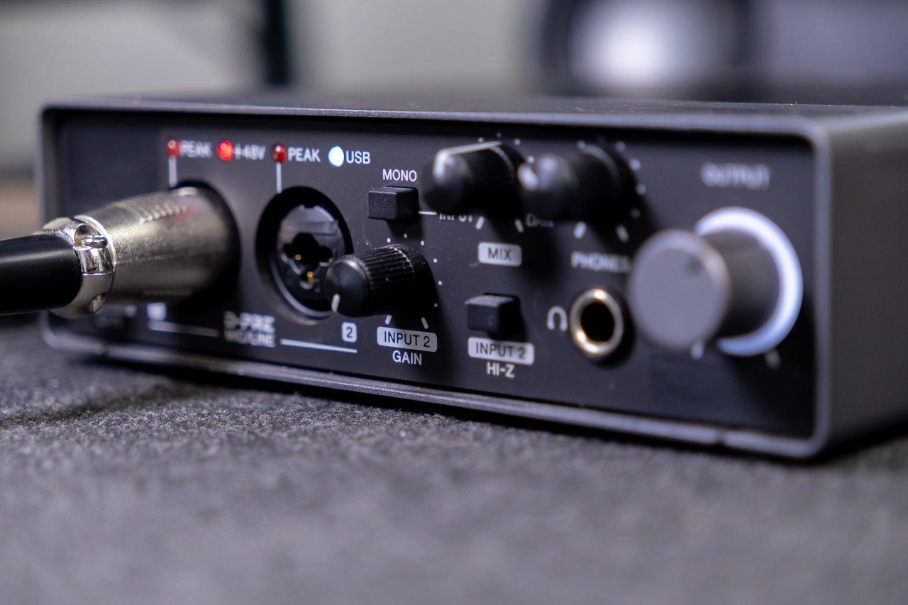 Interface audio USB avec écran et indicateurs de buffer, essentielle pour optimiser la latence MIDI en studio.