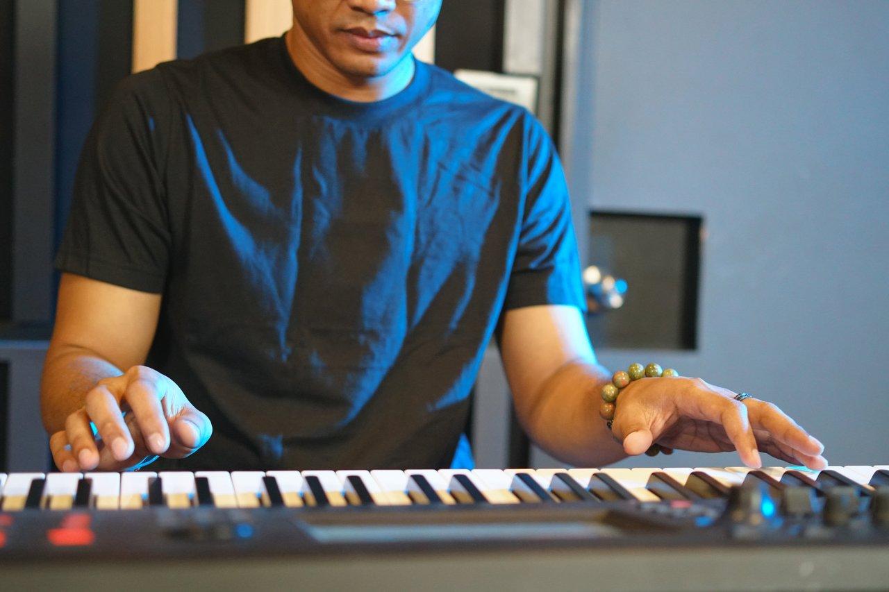 Jeune adulte jouant sur un clavier lourd 88 touches avec ambiance lumineuse.