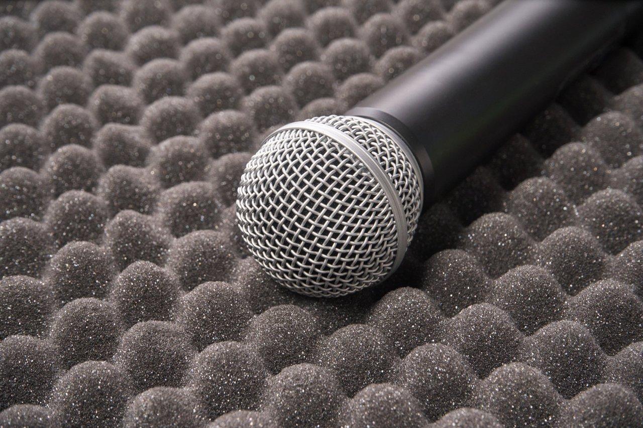 Musiciens en répétition utilisant des microphones avec panneaux acoustiques pour une meilleure directivité supercardioïde.