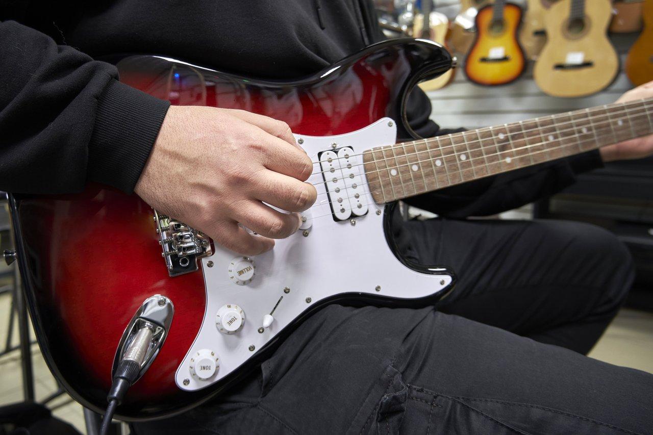 Routine de pratique de guitare électrique avec métronome et partitions sur une table de travail.