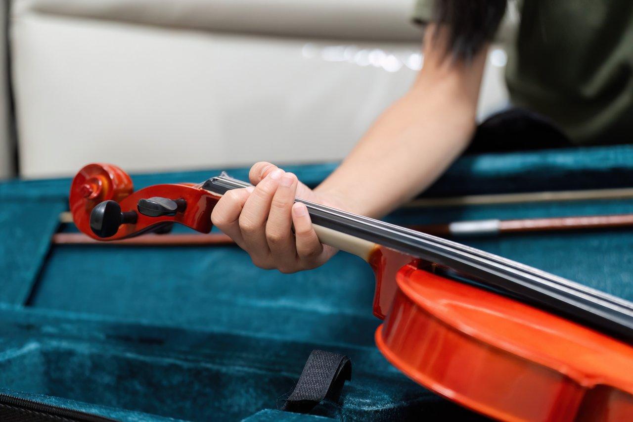 Un violoniste débutant tenant un archet avec une protection de tête pour un apprentissage en toute sécurité.