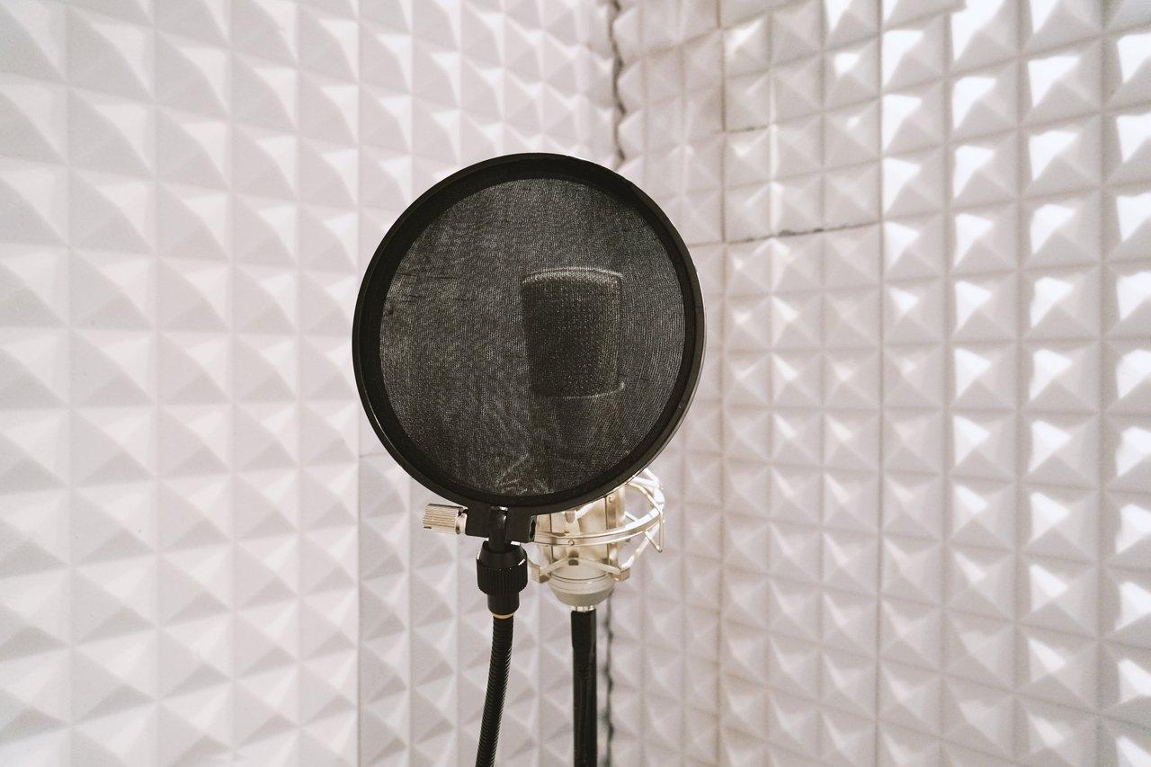 Vue d'une cabine vocale insonorisée moderne équipée d’un microphone Neumann pour des enregistrements professionnels.